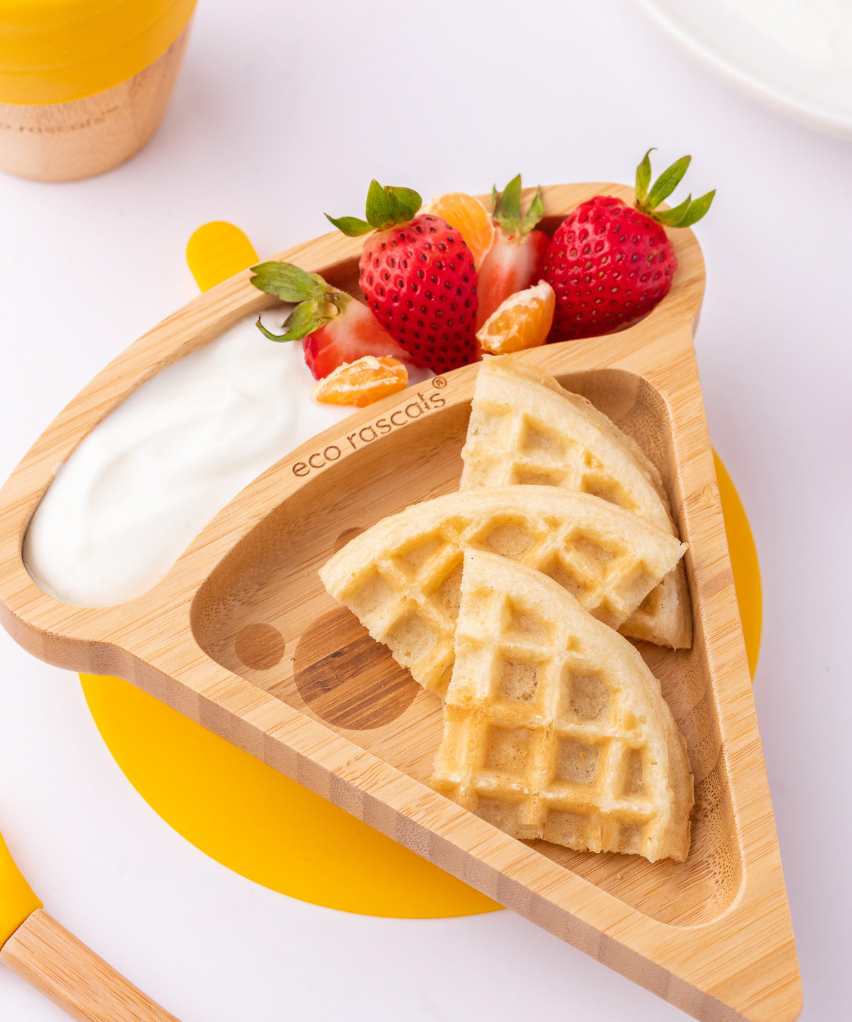 The Eco Rascals Pizza Bamboo Suction Plate with food inside, waffles are placed in the large triangle section and fruit and yoghurt are in the smaller curved section above. 