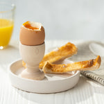 Eco Living wooden egg cup on a dish with an egg on top and 2 small slices of toast 