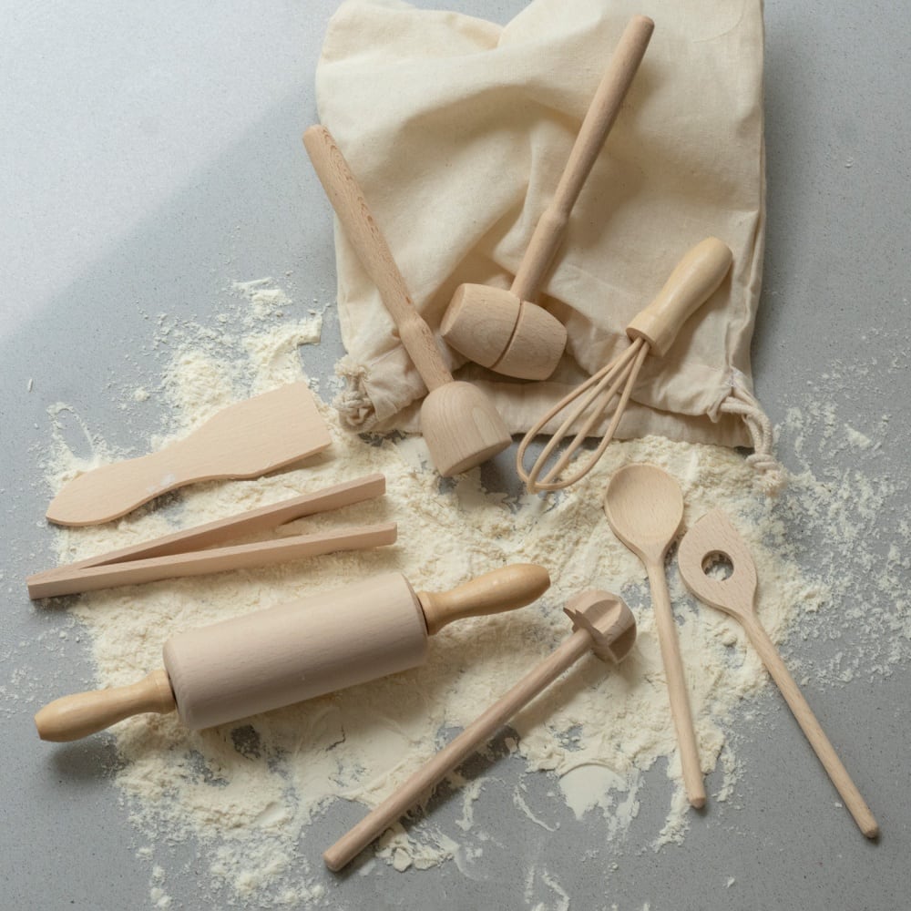 Evolving wooden mini kitchen utensil set laid on its natural cotton bag