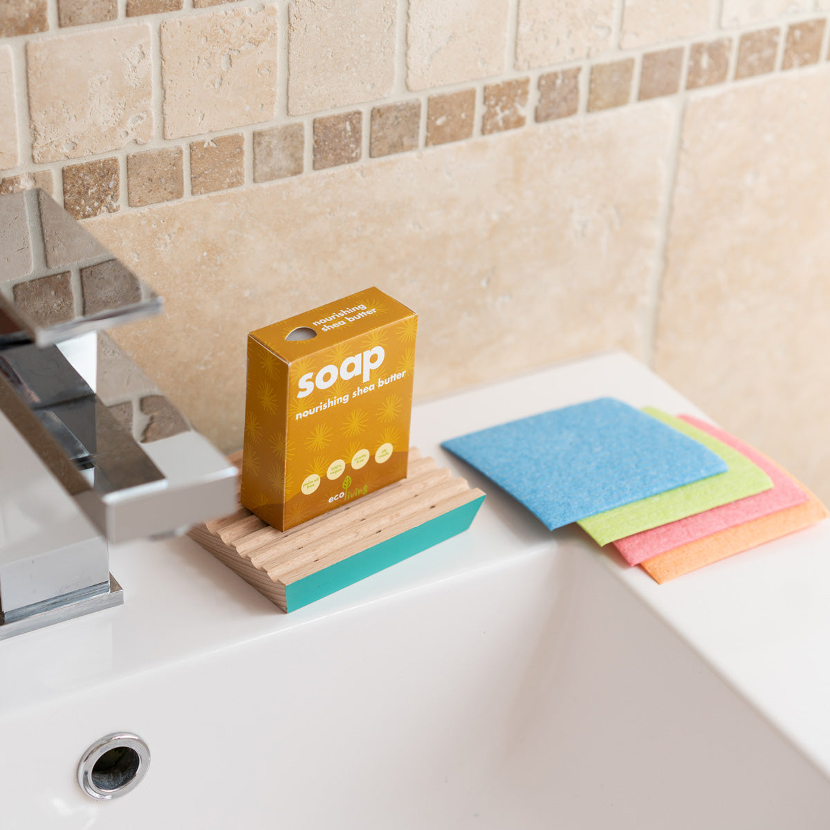 Ecoliving solid shea butter soap bar on a wooden soap dish next to some coloured cleaning cloths