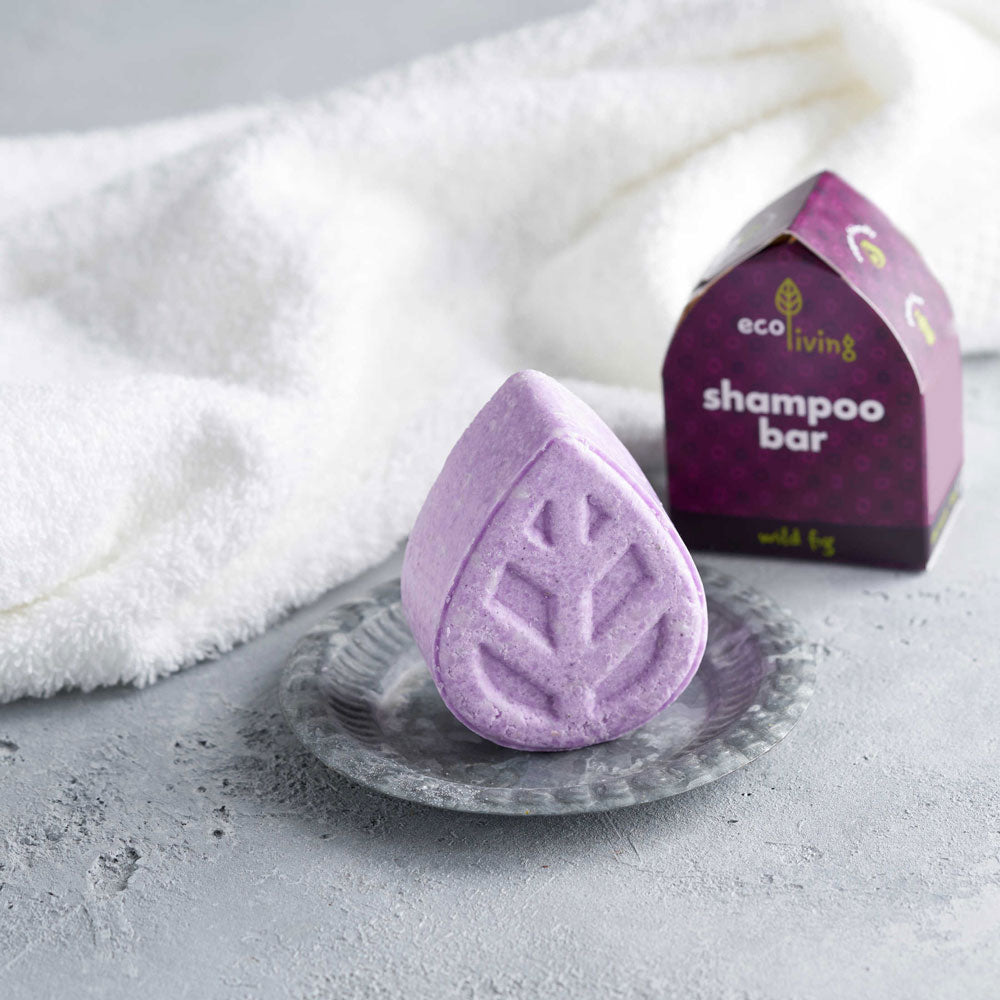 Ecoliving leaf shaped Solid Shampoo Bar in Wild Fig scent placed on a small metal dish with box and white fluffy towel behind