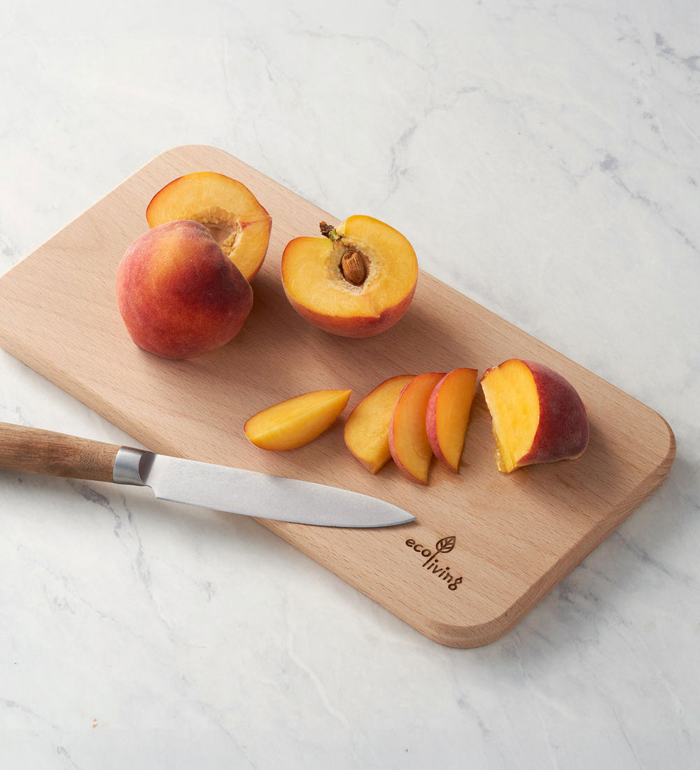 Eco Living wooden chopping board with branding on the corner and sliced peached on top 