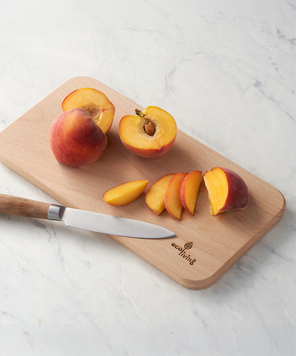 Eco Living wooden chopping board with branding on the corner and sliced peached on top 