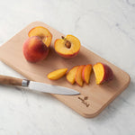 Eco Living wooden chopping board with branding on the corner and sliced peached on top 