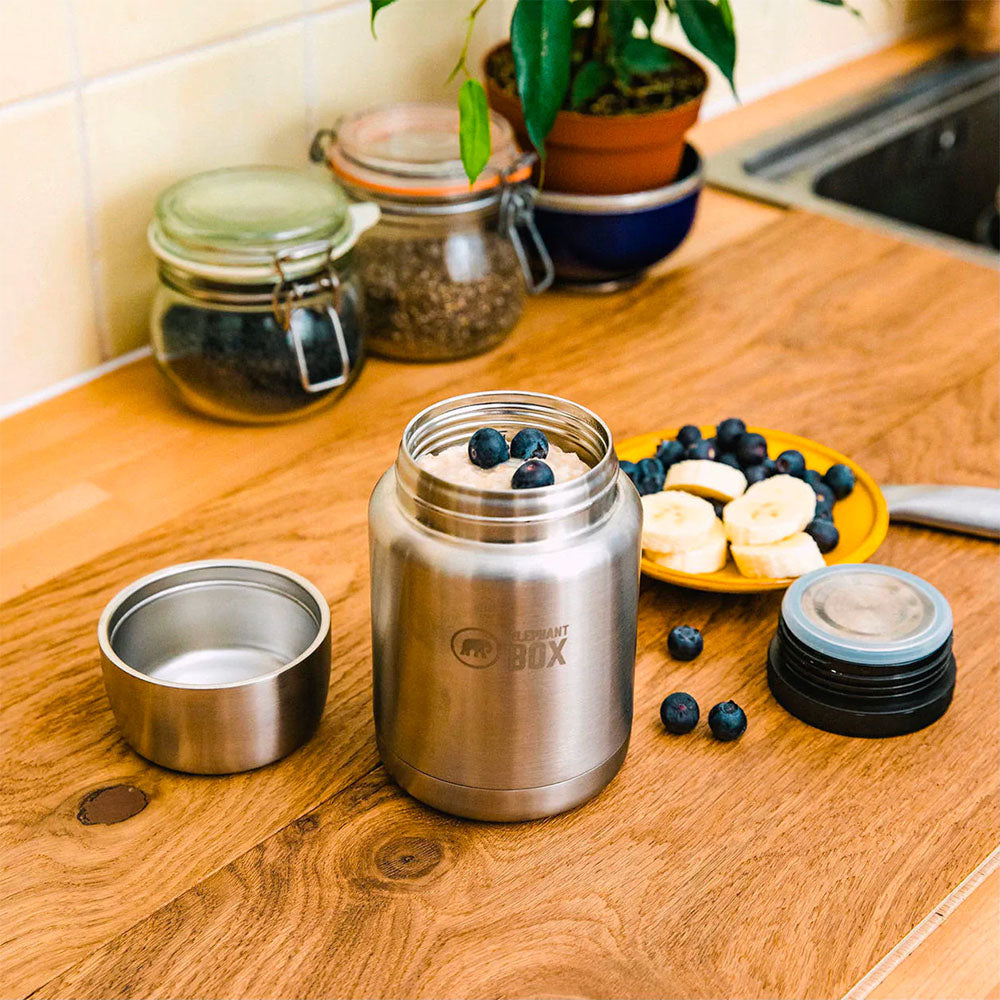 Close up of the Elephant Box eco-friendly steel food flask filled with porridge and berries on a wooden worktop