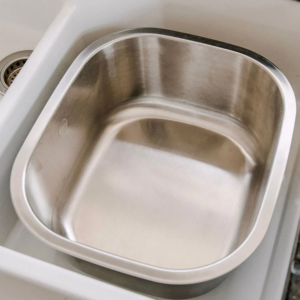 a cup and a glass being cleaned with a wooden washing up brush