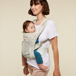 A woman babywearing a young baby using the ErgoBaby Aerloom abalone Baby Carrier.