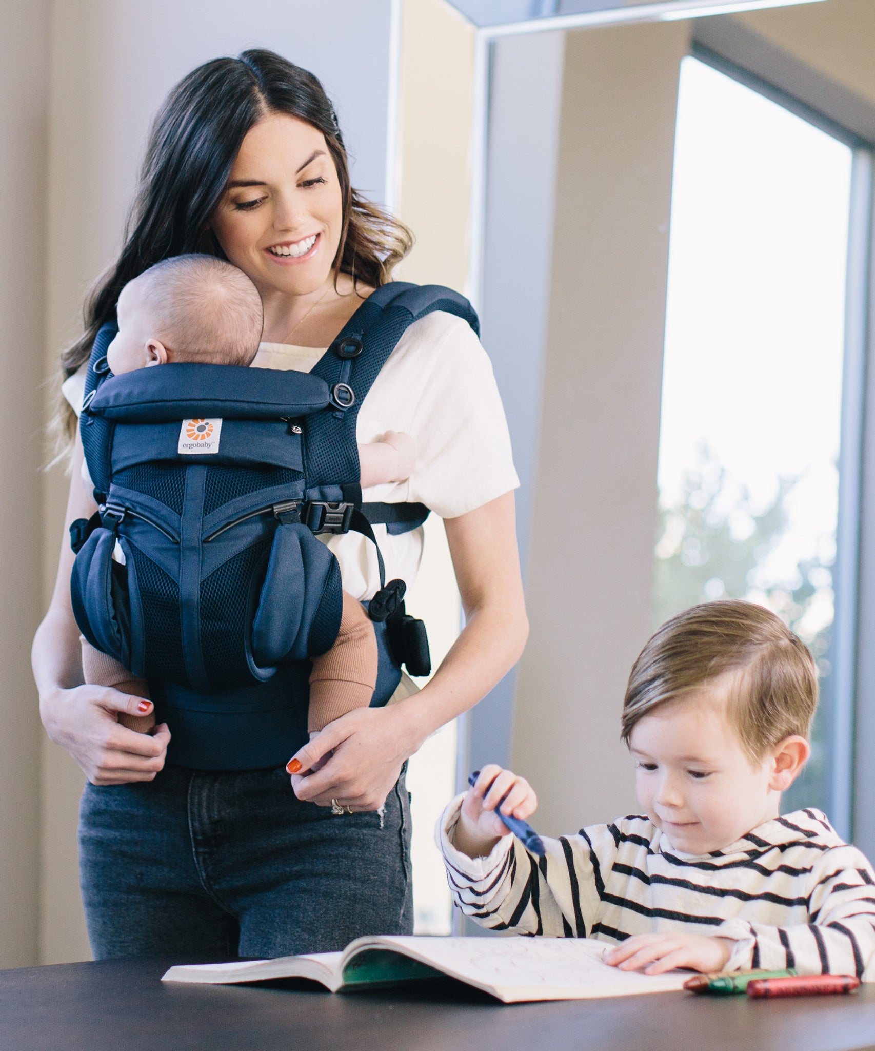 A woman babywearing her baby using a midnigh blue coloured Ergobaby Omni 360 Cool Air Mesh Baby Carrier