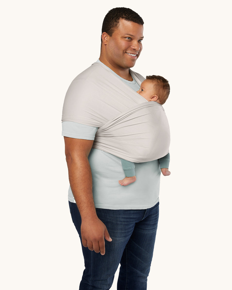 An adult is wearing the Ergobaby Aura Wrap Baby Carrier in Grey