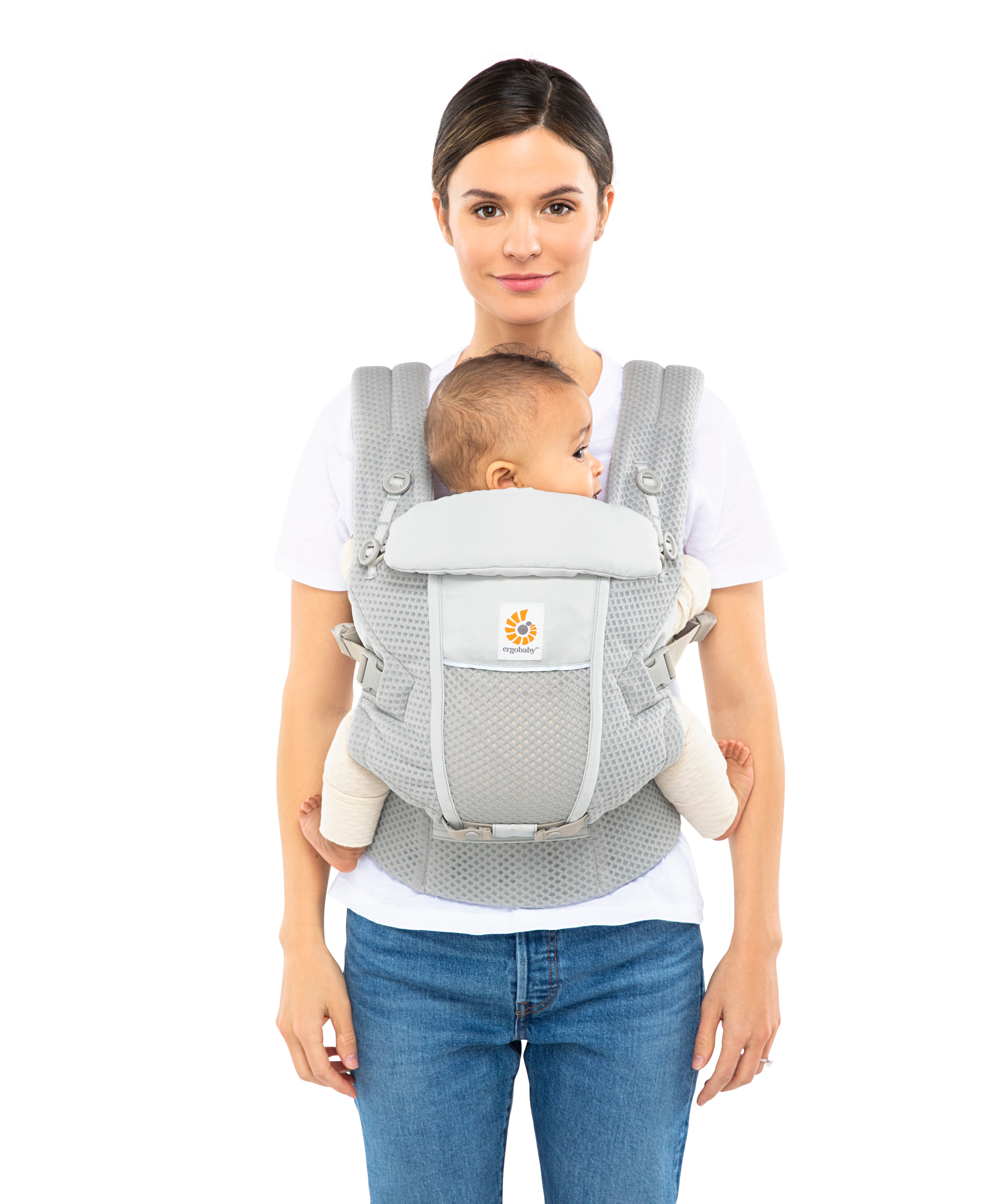 Woman with brown hair tied back and a white t-shirt wearing her baby in the Ergobaby Adapt  SoftFlex™ Mesh Baby Carrier in Pearl Grey. Front view, white background. 