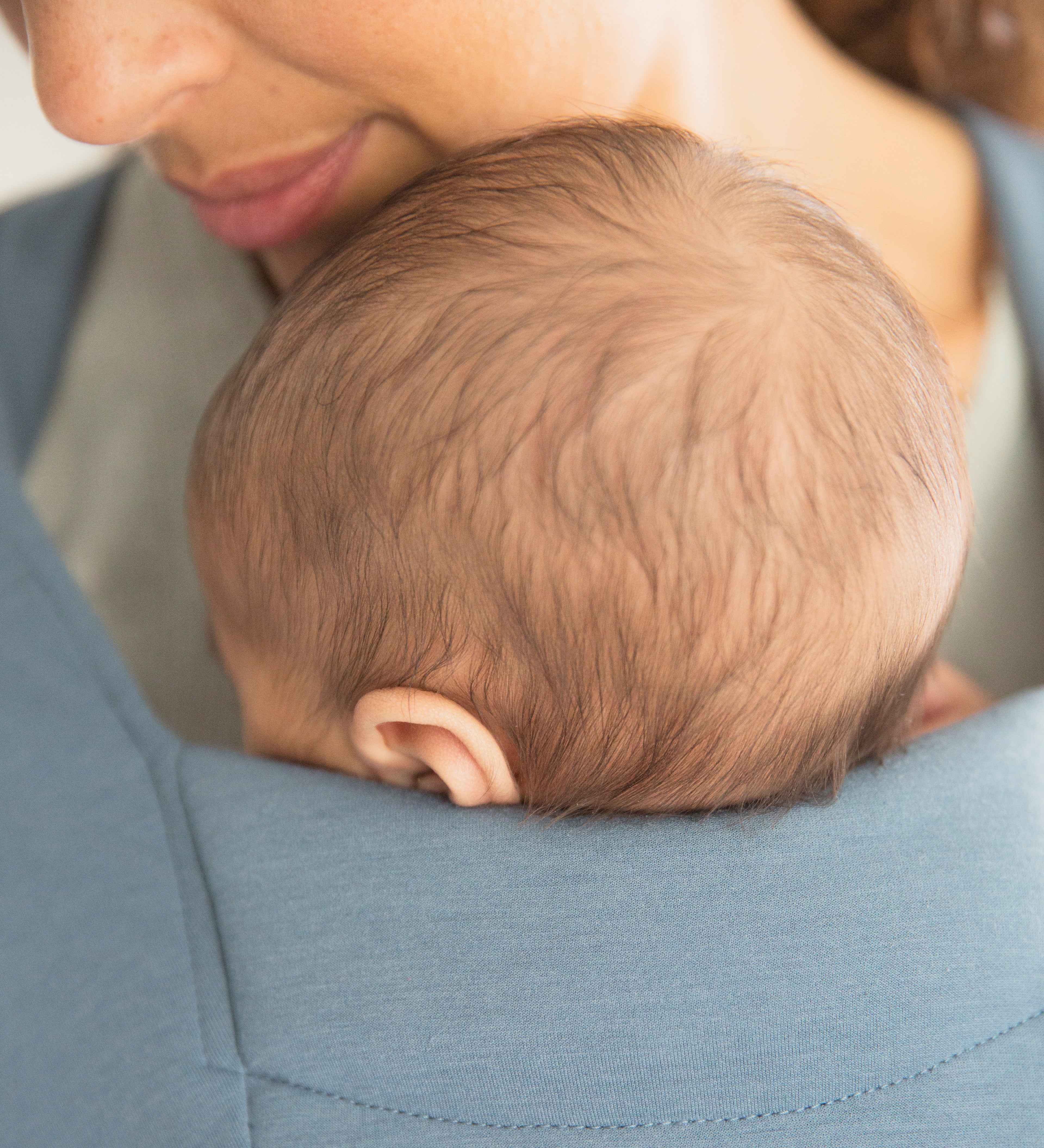 Close up of baby's head facing inwards in the Ergobaby Embrace Soft Knit Newborn Baby Carrier in Oxford Blue. 