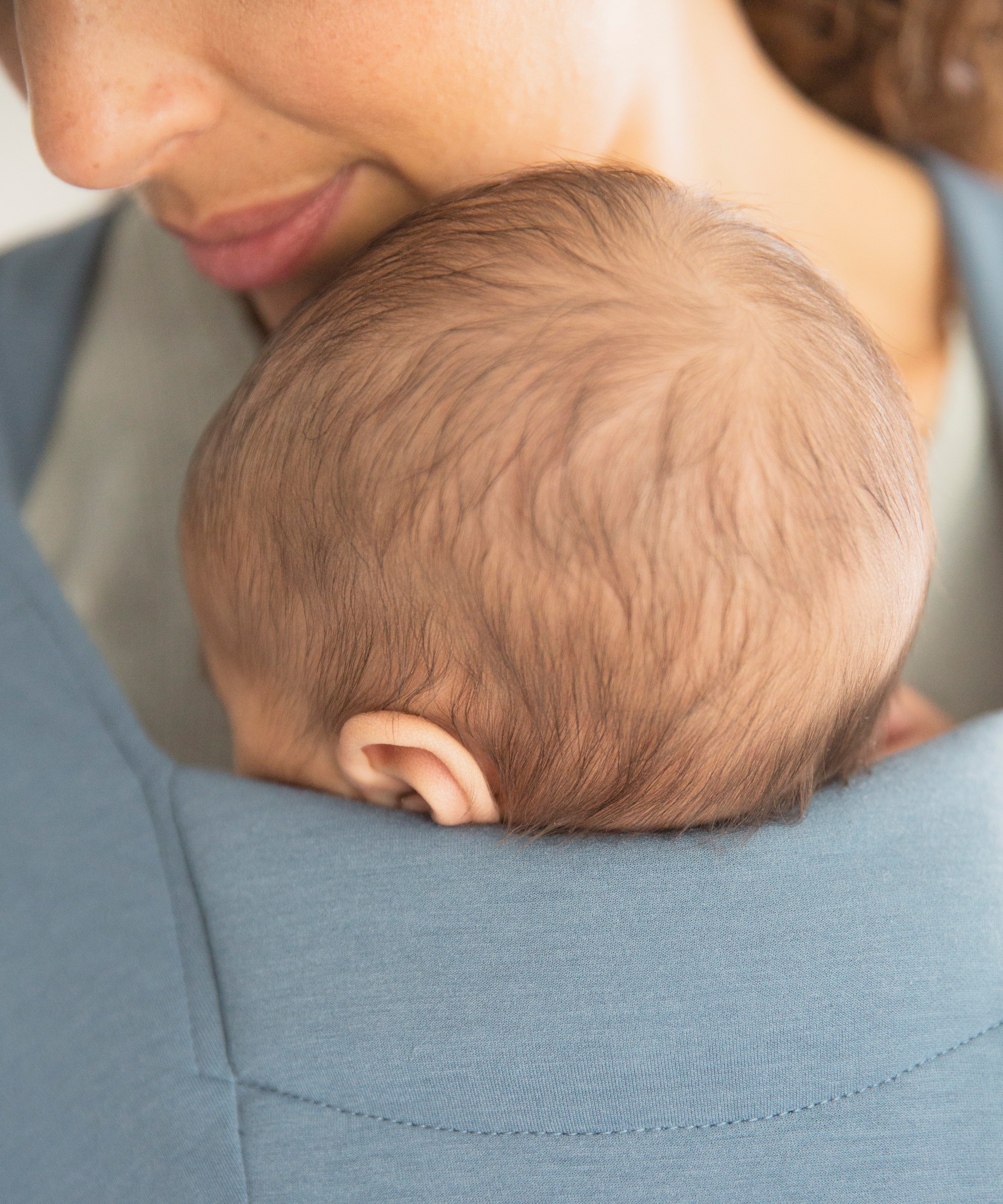 Close up of baby's head facing inwards in the Ergobaby Embrace Soft Knit Newborn Baby Carrier in Oxford Blue. 