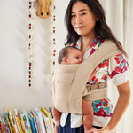 A woman babywearing using the Ergobaby Embrace Soft Air Mesh Newborn Baby Carrier in cream.