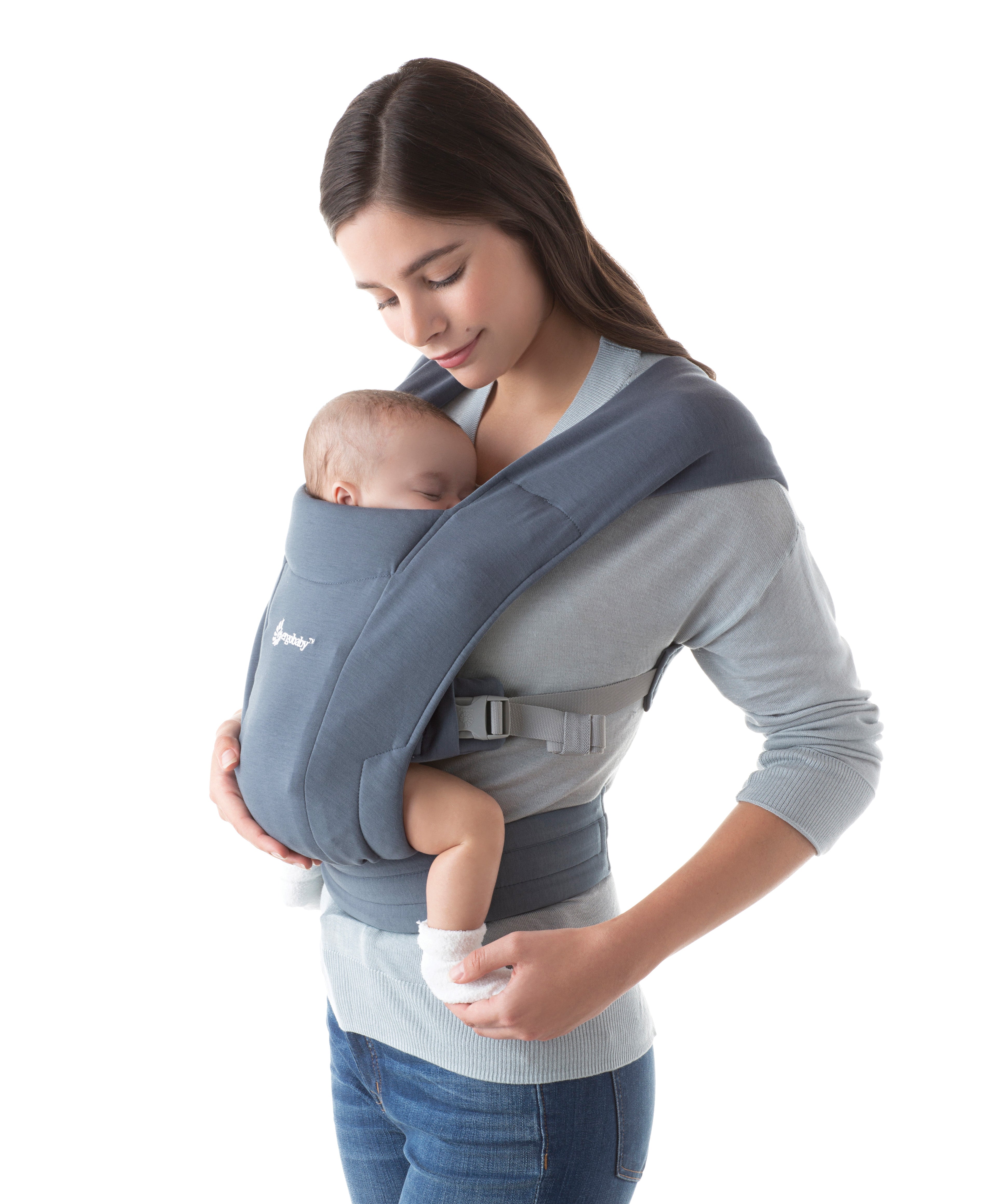 Woman wearing a grey top and her baby on her front facing inwards in the Ergobaby Embrace Soft Knit Newborn Baby Carrier in Oxford Blue. Side view, white background.