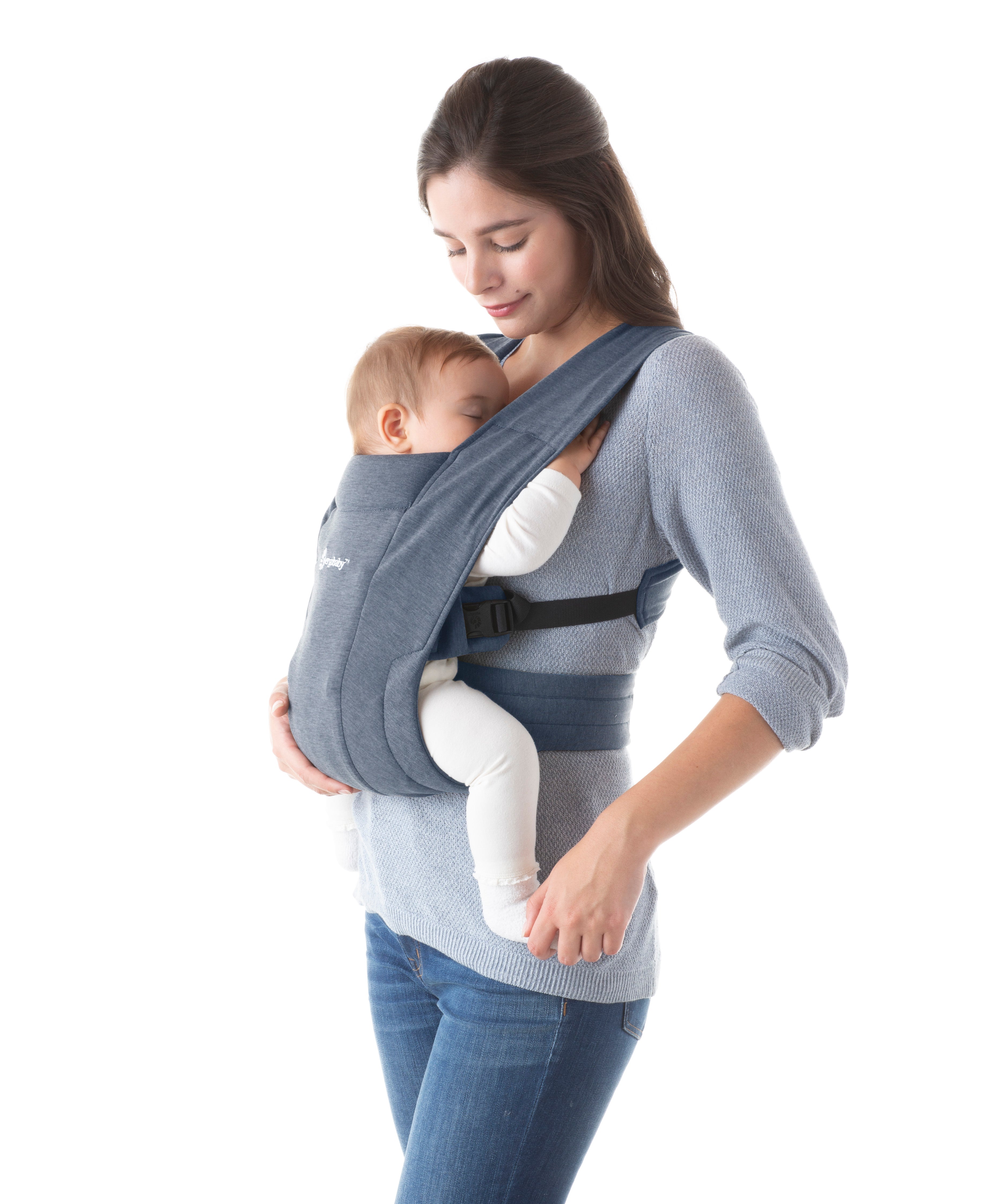 Woman wearing a grey top and her baby on her front facing inwards in the Ergobaby Embrace Soft Knit Newborn Baby Carrier in Oxford Blue. Side view, white background.