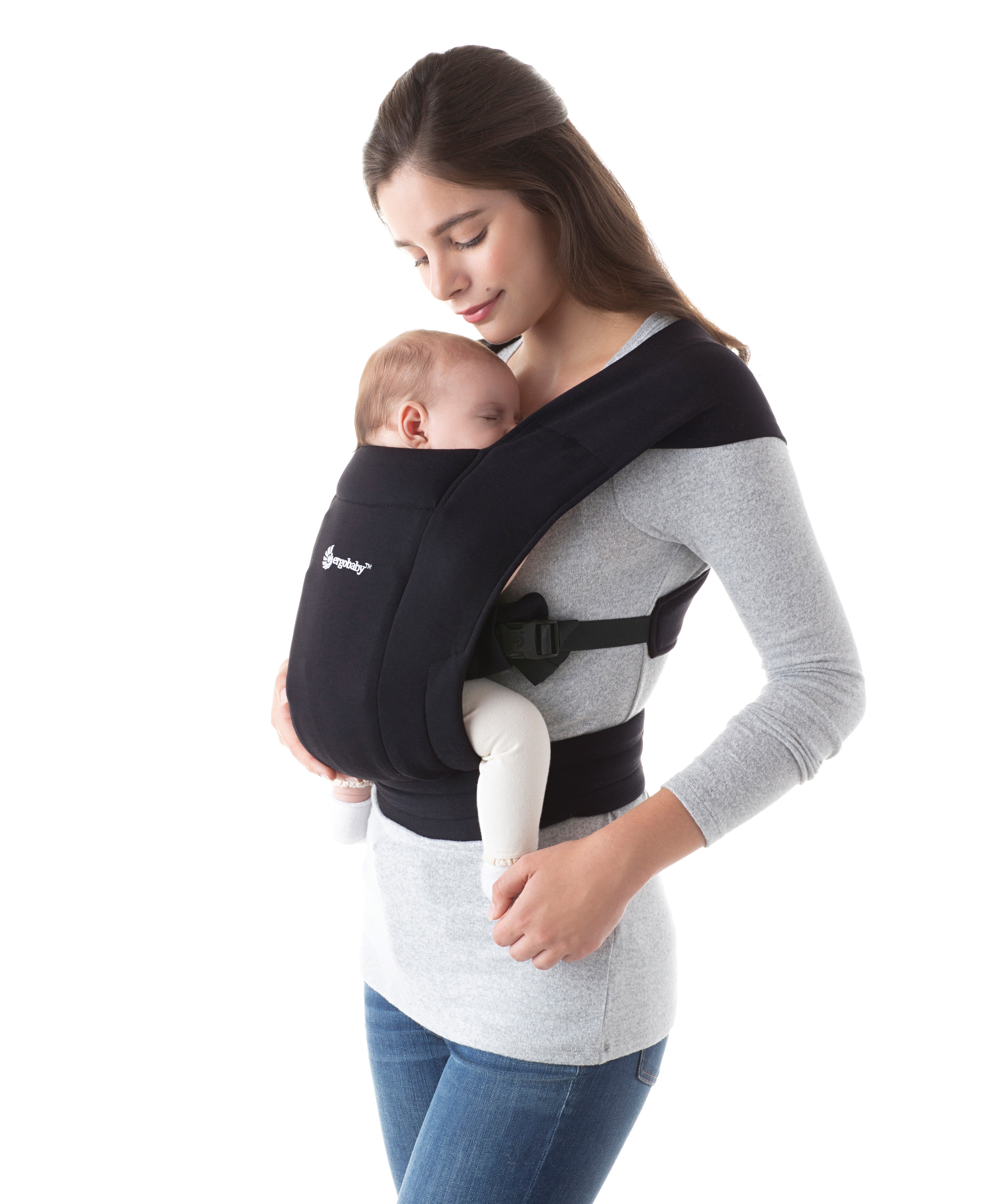 Woman wearing a grey top and her sleeping baby on her front in the Ergobaby Embrace Soft Knit Newborn Baby Carrier in Pure Black. Side view white background.