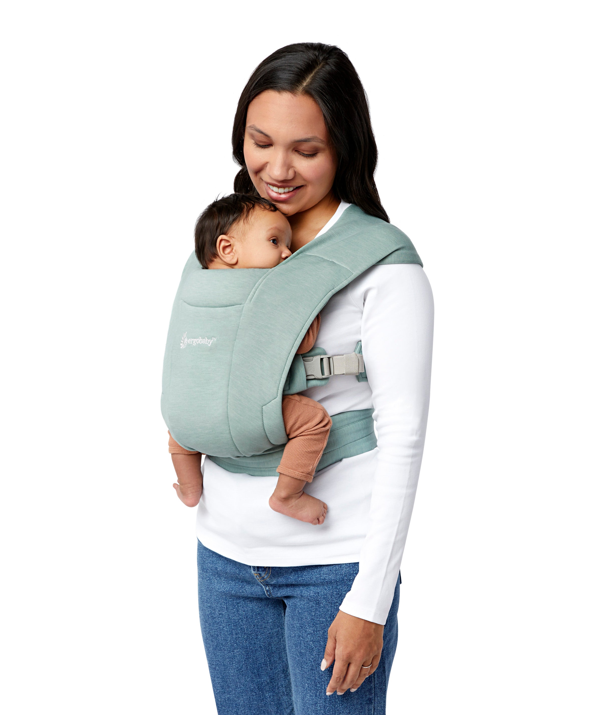 Woman wearing a white top and her baby on her front facing inwards in the Ergobaby Embrace Soft Knit Newborn Baby Carrier in Jade. Side view white background.