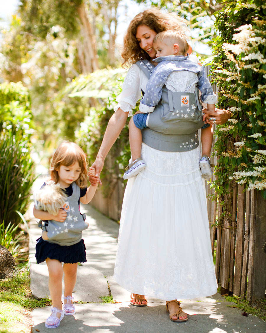  and both are wearing matching carriers. The child is wearing the Kids Doll Carrier