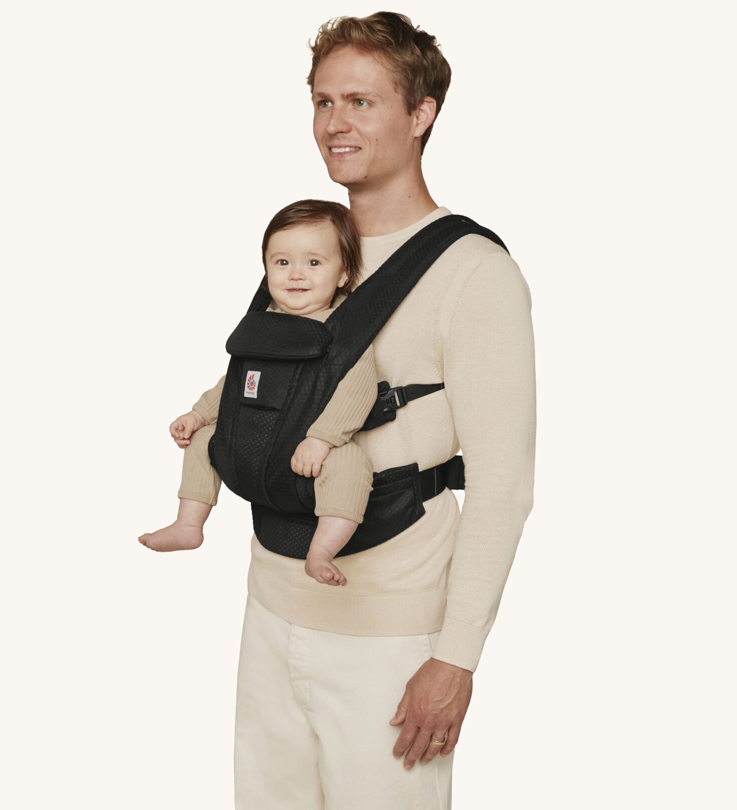 A man wearing the Ergobaby Omni Deluxe Mesh baby carrier in Onyx Black, with a little baby being carried facing outwards. 