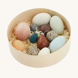 A wooden basket filled with a dozen uniquely painted wooden duck eggs from Erzi.