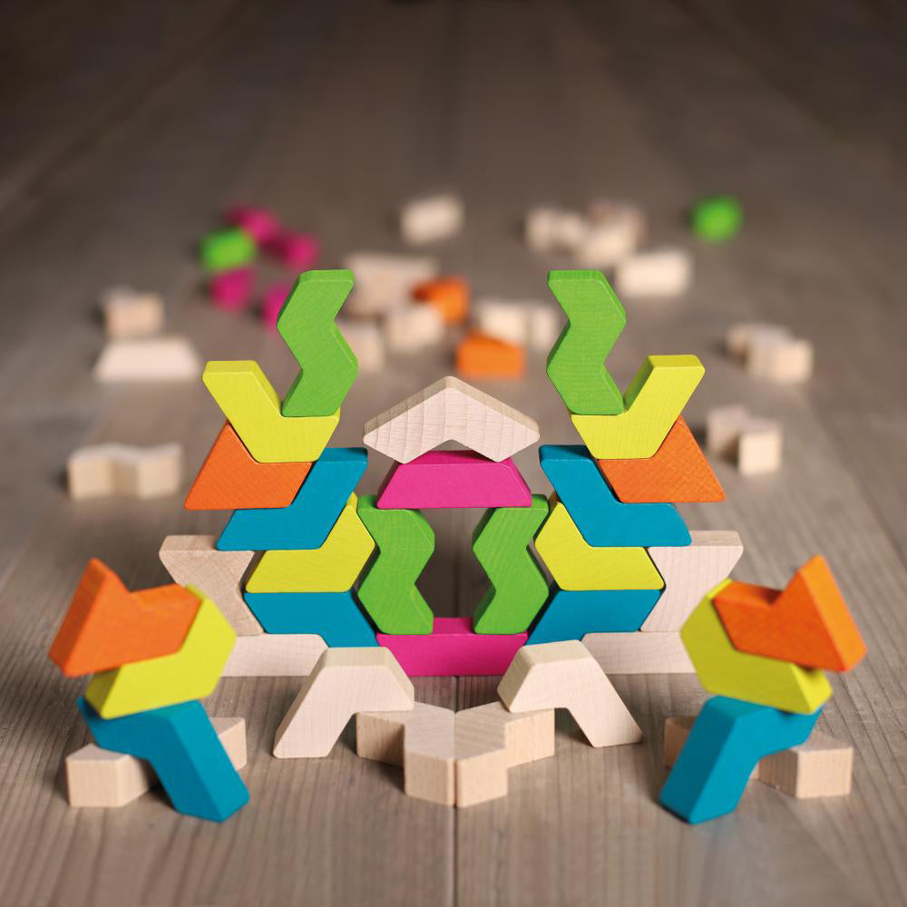 Bits of the Erzi solid wooden rainbow stacking shapes built into a geometric tower on a wooden floor