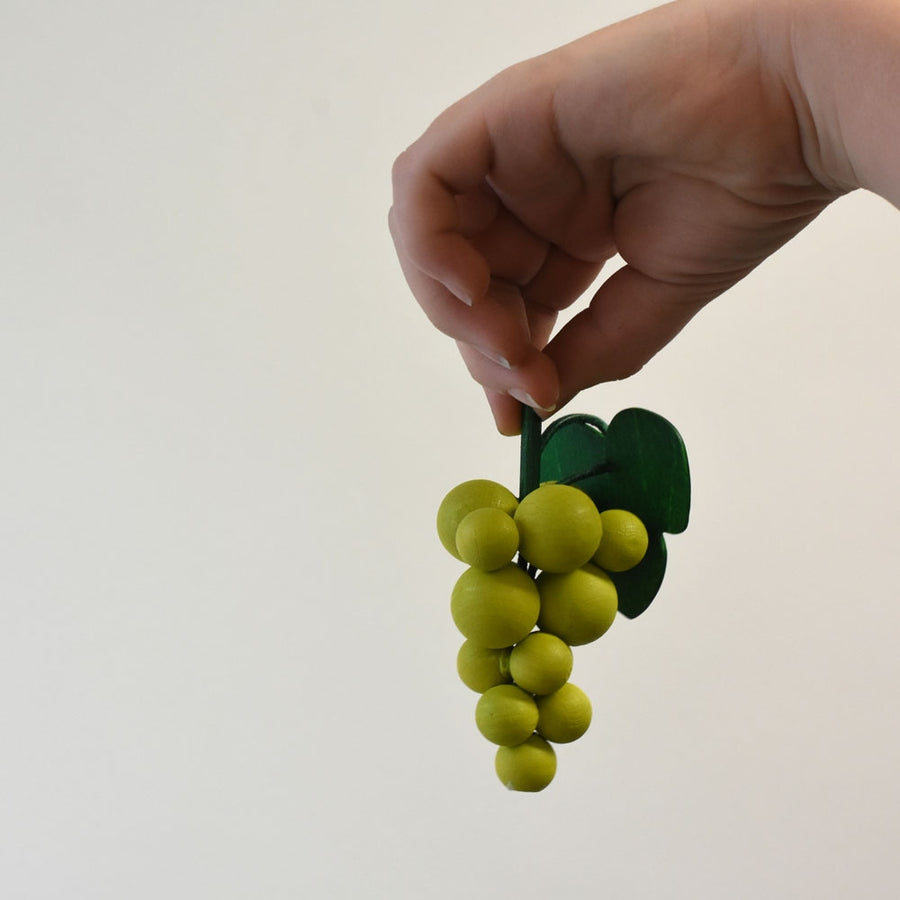 Hand holding the Erzi Bunch Of Green Grapes Wooden Play Food.