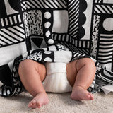 A Etta Loves x Camille Walala XL Muslin Square - Mono hung up, a baby's legs and feet can be seen popping out from underneath.