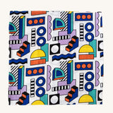 A Etta Loves x Camille Walala XL Muslin Square in shapes design folded up into a square on a plain background. 