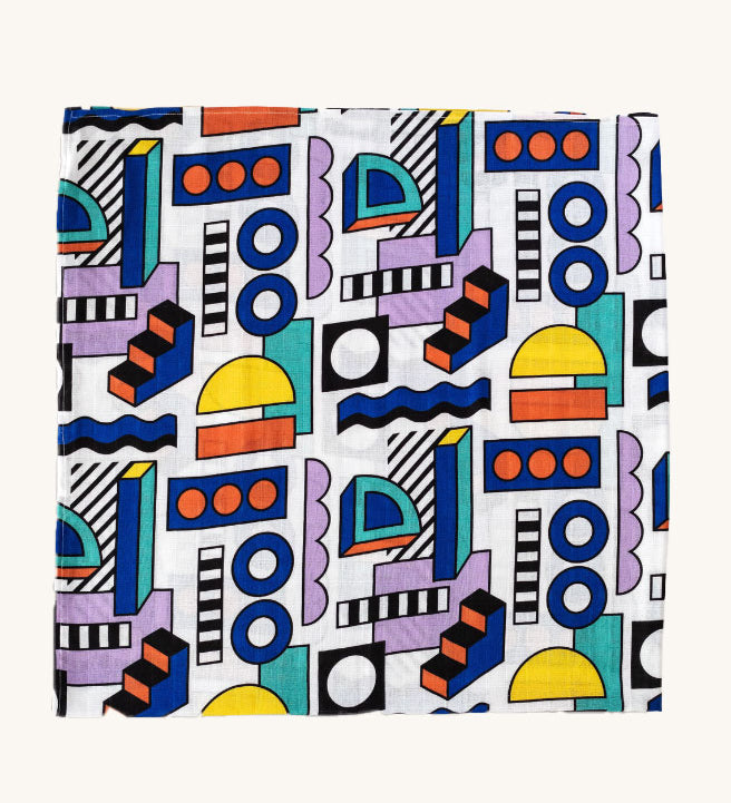 A Etta Loves x Camille Walala XL Muslin Square in shapes design folded up into a square on a plain background. 