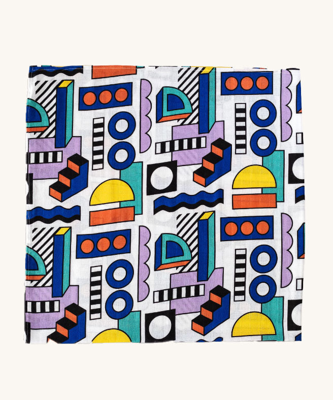 A Etta Loves x Camille Walala XL Muslin Square in shapes design folded up into a square on a plain background. 