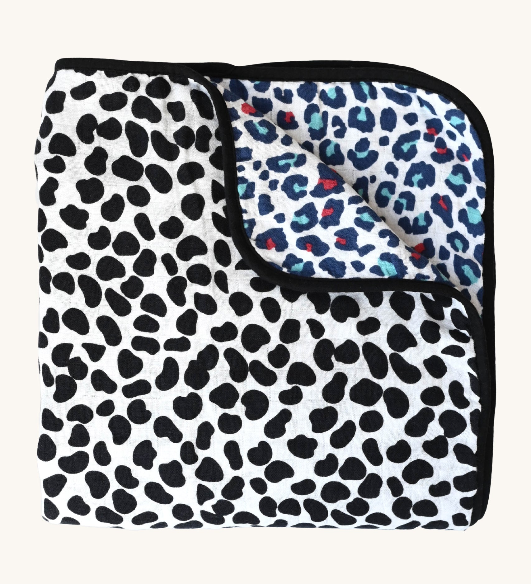 The Etta Loves Reversible Organic Cotton Muslin Blanket - Animal Print, with a fun, black, spotty Dalmatian print on one side, and a colourful Leopard print on the other