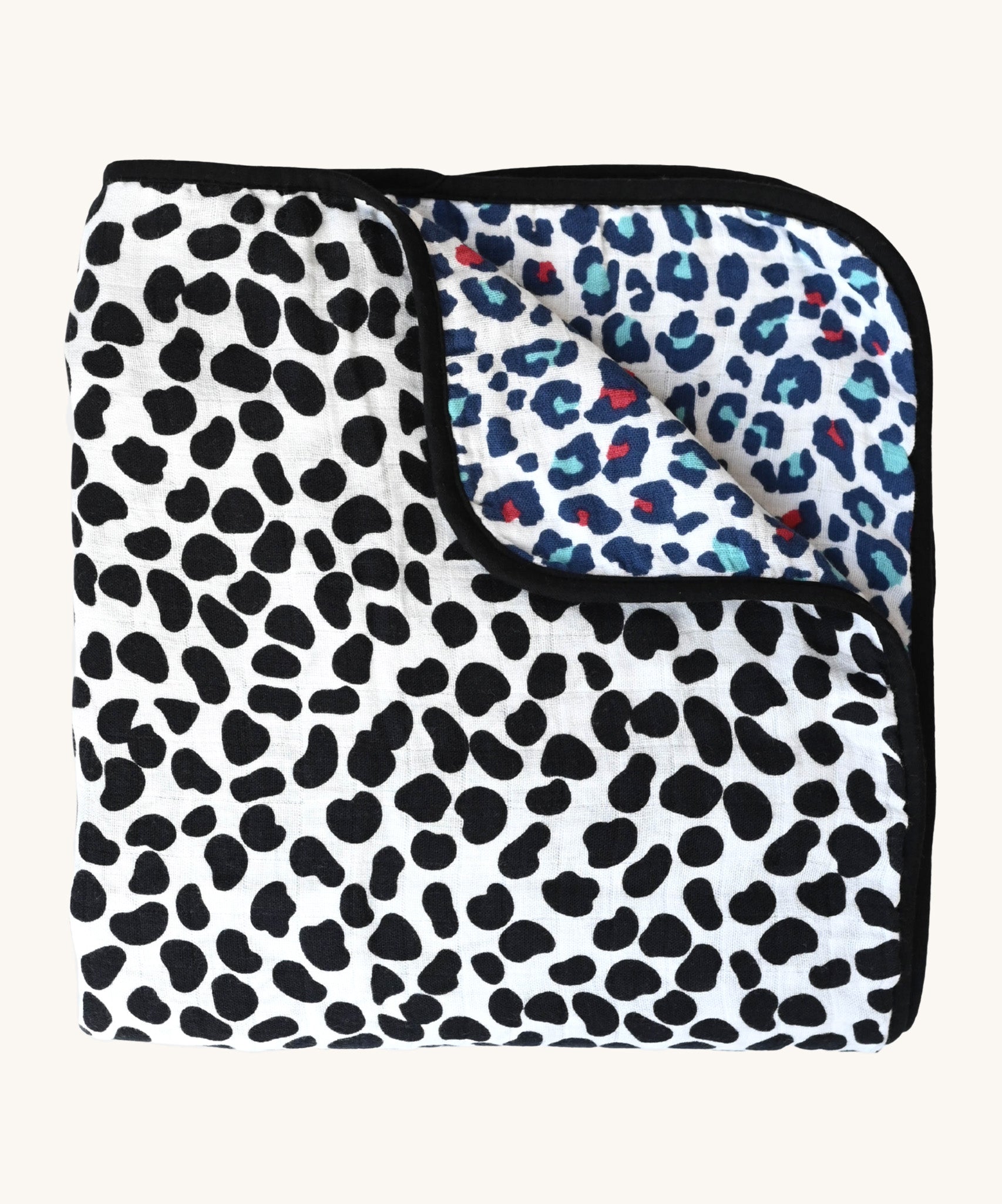 The Etta Loves Reversible Organic Cotton Muslin Blanket - Animal Print, with a fun, black, spotty Dalmatian print on one side, and a colourful Leopard print on the other