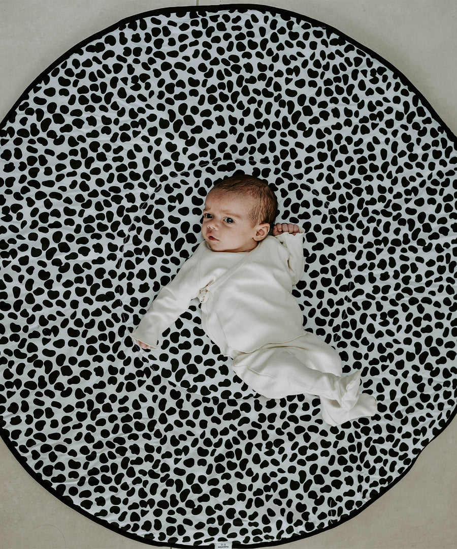 A baby lying down and looking at the black