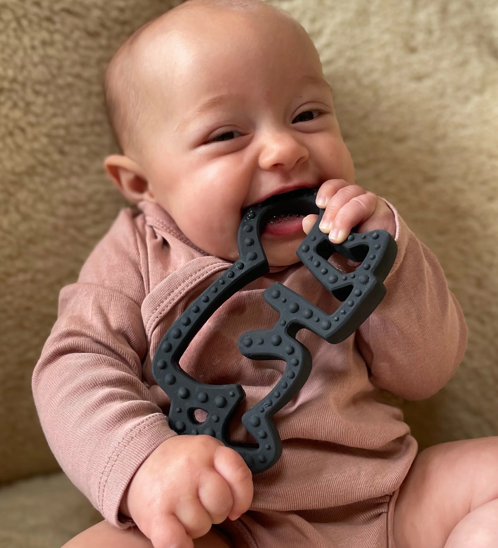 A baby chewing and plaing with the Etta Loves X Keith Haring Natural Rubber Sensory Teether - Baby