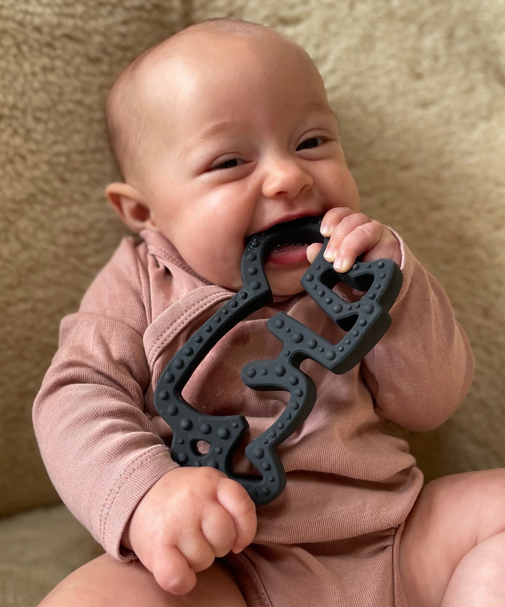 A baby chewing and plaing with the Etta Loves X Keith Haring Natural Rubber Sensory Teether - Baby