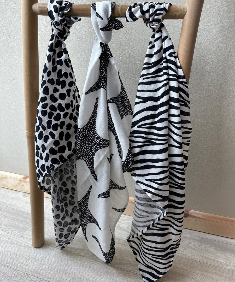 Three Etta Loves XL Muslin clothes tied to a wooden bamboo ladder in Leopard Print