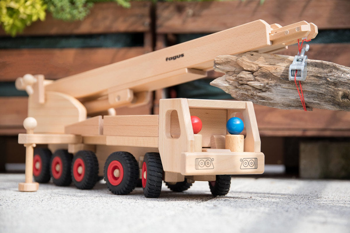 Close up of the Fagus handmade wooden crane toy carrying a small log