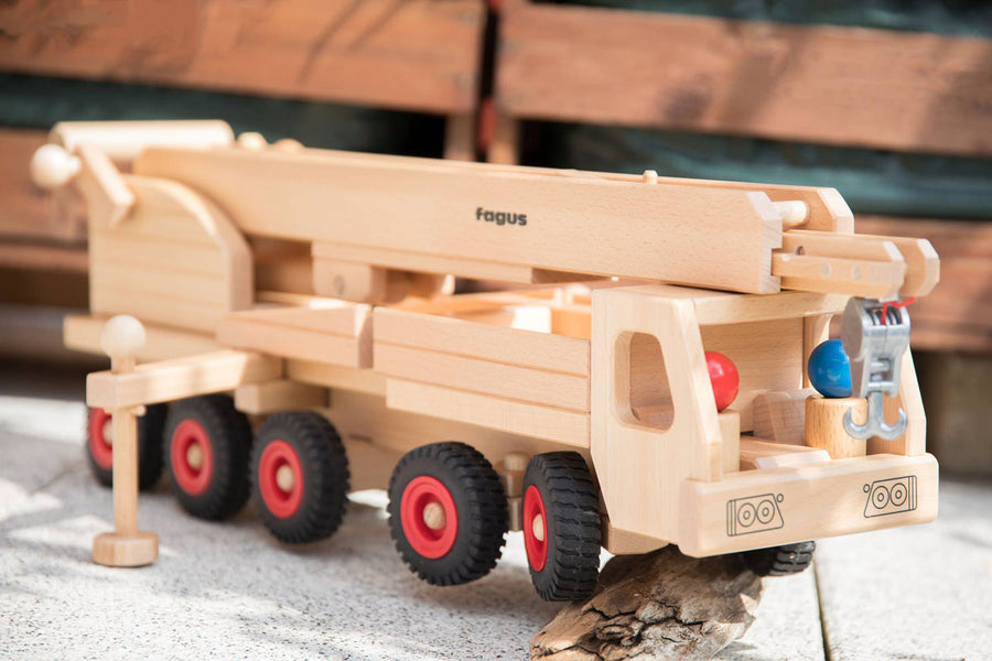 Close up of the Fagus eco-friendly mobile crane toy with its crane down on a grey concrete slab