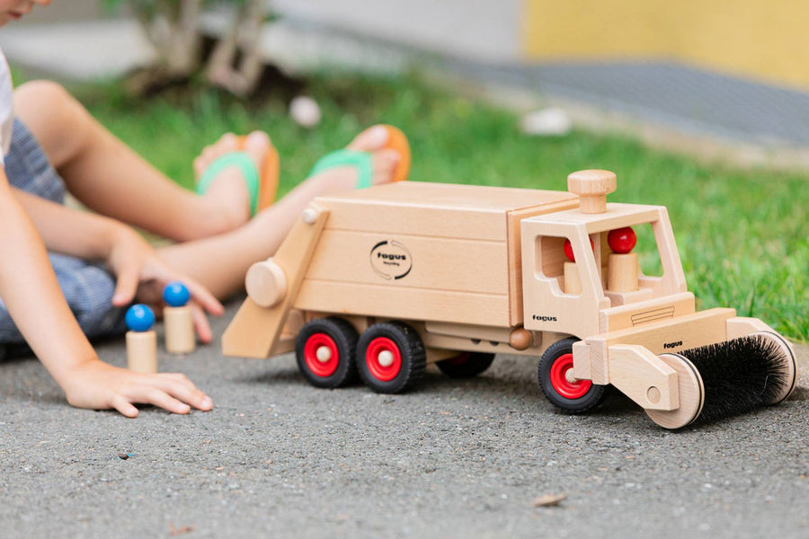 Child playing with the Fagus handmade wooden sweeper accessory toy attached to the Fagus garbage tipper truck