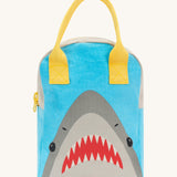 Fluf zip lunch bag in light blue and grey with a design of a shark's head on the bottom with a yellow handle and zip detail on a cream background.