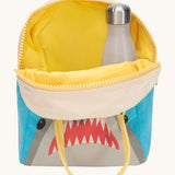 Fluf zip shark lunch bag inside lining in yellow with a bottle packed inside Outside is a blue and grey bag with a design of a shark's head on the bottom with a yellow handle and zip detail on a cream background. 