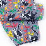 Close up of the Frugi Rowenna outfit, lemur laugh showing the printed lemurs next to different coloured leaves and leg cuff details on the bottoms  on light purple organic cotton fabric