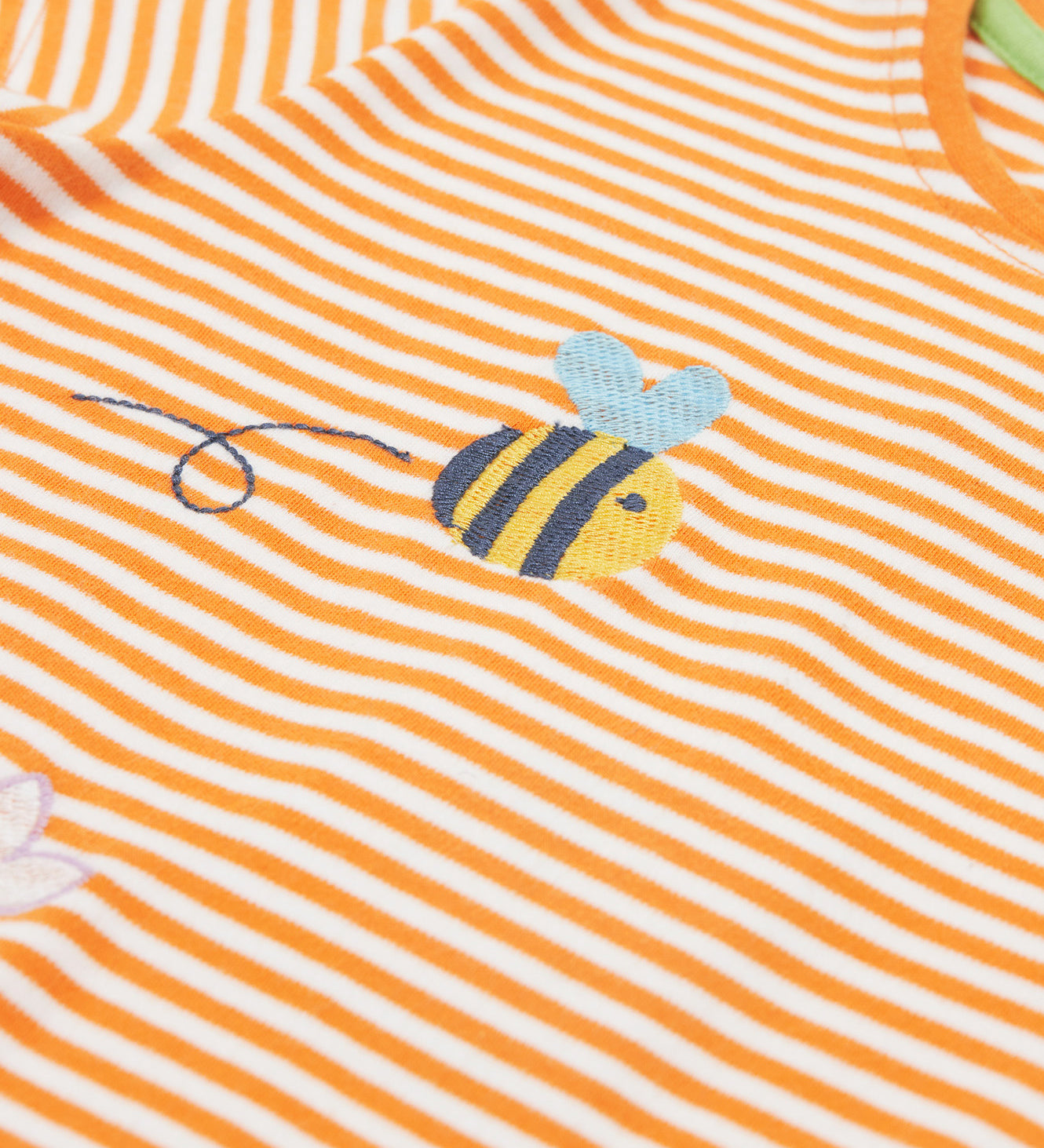 Close up of the Frugi kids lifeboat stripe veg t-shirt. Showing the bee applique with grey wings on orange and white stripe organic cotton fabric