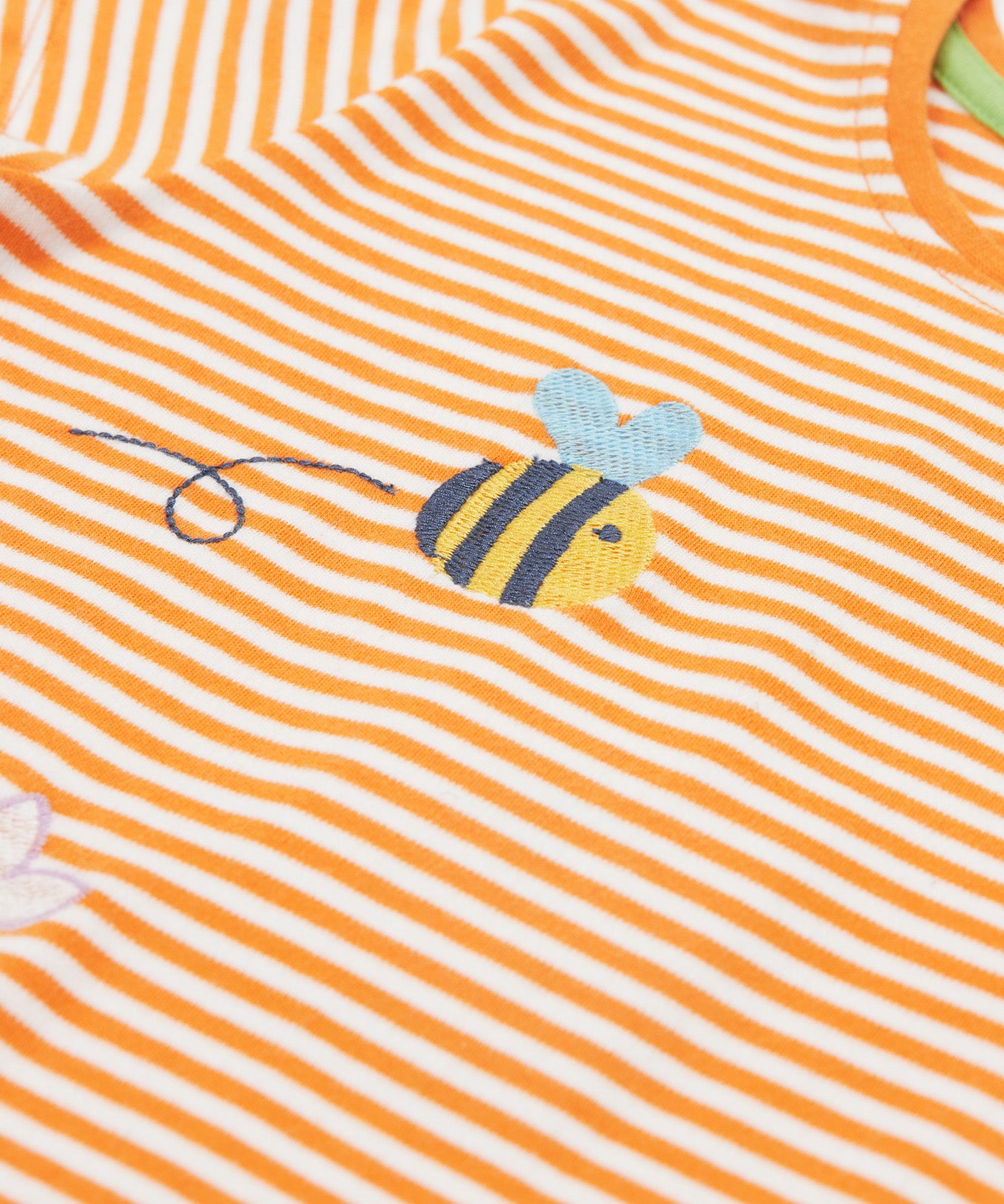 Close up of the Frugi kids lifeboat stripe veg t-shirt. Showing the bee applique with grey wings on orange and white stripe organic cotton fabric