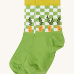 Close up of the baby farm field sock. Showing the carrot print on green check design and mustard yellow elasticated cuff on green organic cotton fabric. 