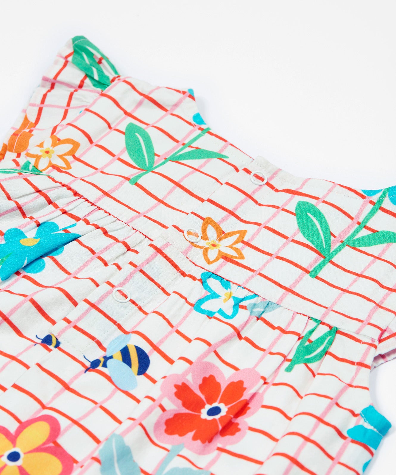 Close up of the Frugi baby Lula paint a floral playsuit. Showing the back popper fastener detail on white and red check organic cotton fabric.