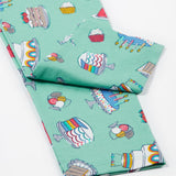 A close up of the Frugi kids let's bake libby leggings. Showing the different cakes, puddings and ice creams design leg cuffs on a light green organic cotton fabric