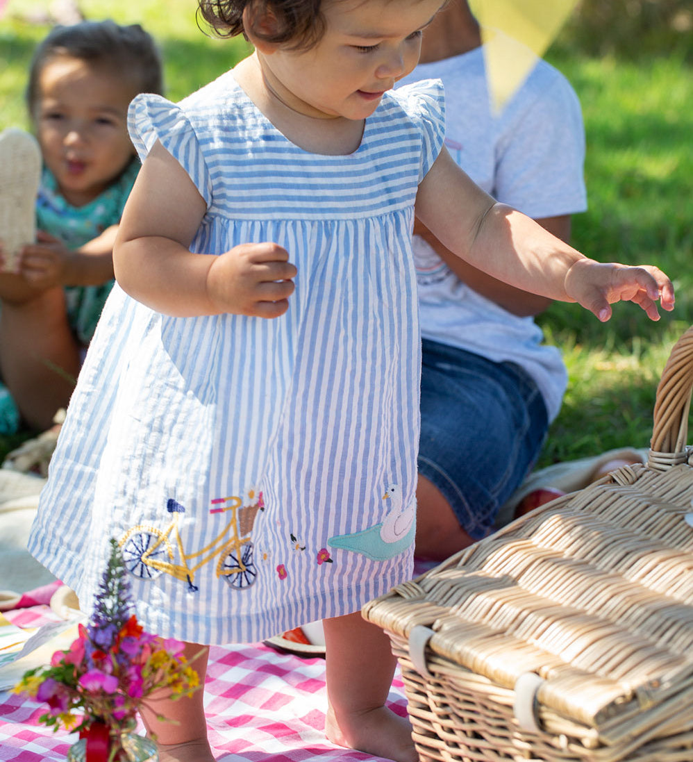 Child wearing the Frugi  Beach Hut Blue Stripe Birdie Body Dress showing the front of the dress