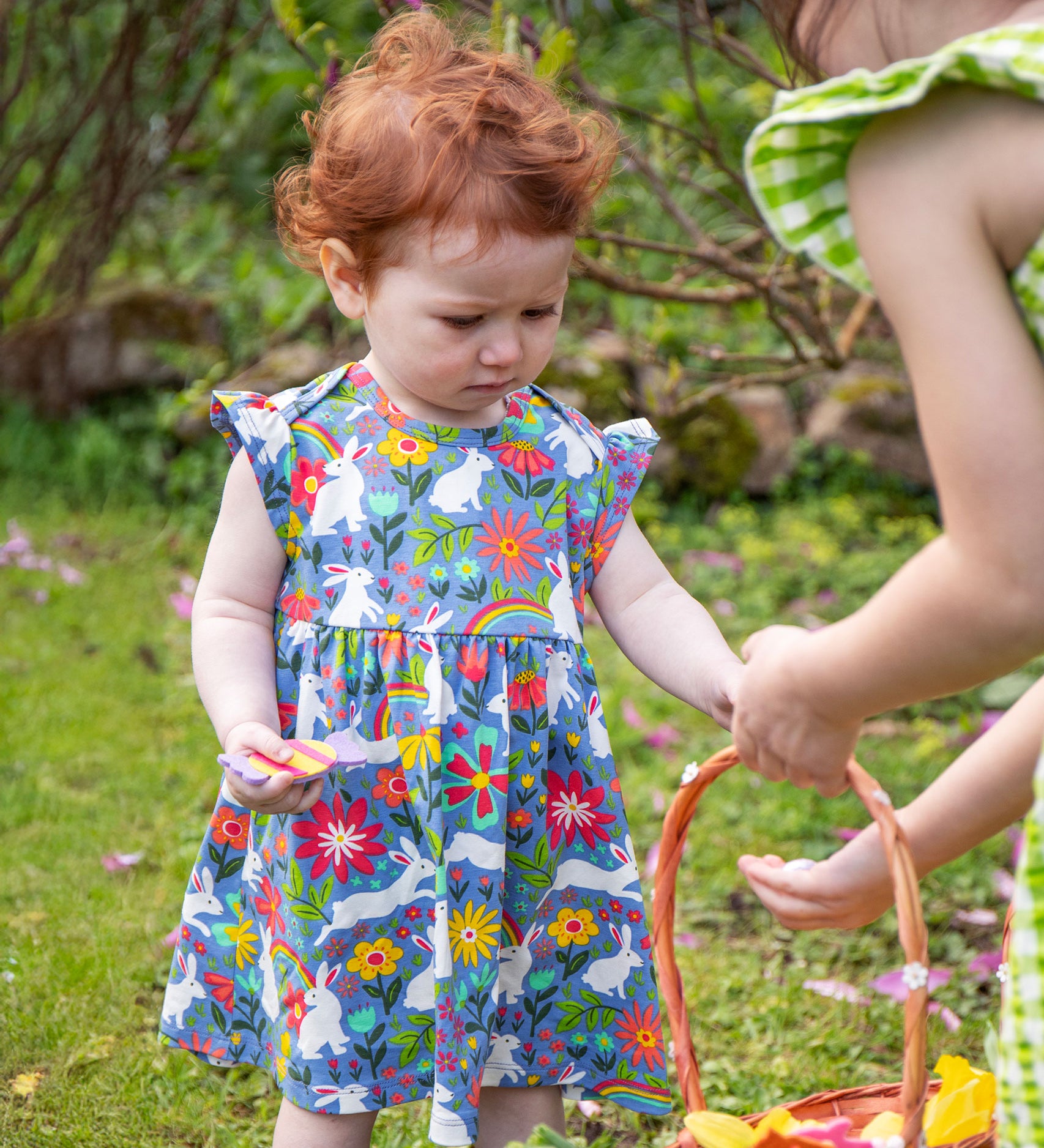 A child wearing a Frugi Baby Bella Organic Cotton Dress with a Bunny Bounce print design.