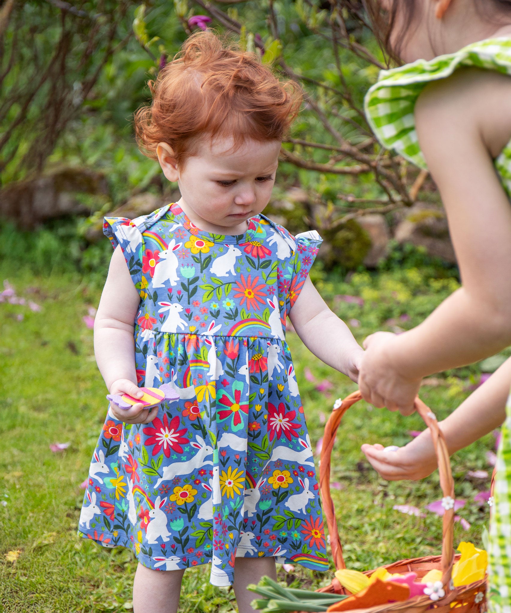 A child wearing a Frugi Baby Bella Organic Cotton Dress with a Bunny Bounce print design.